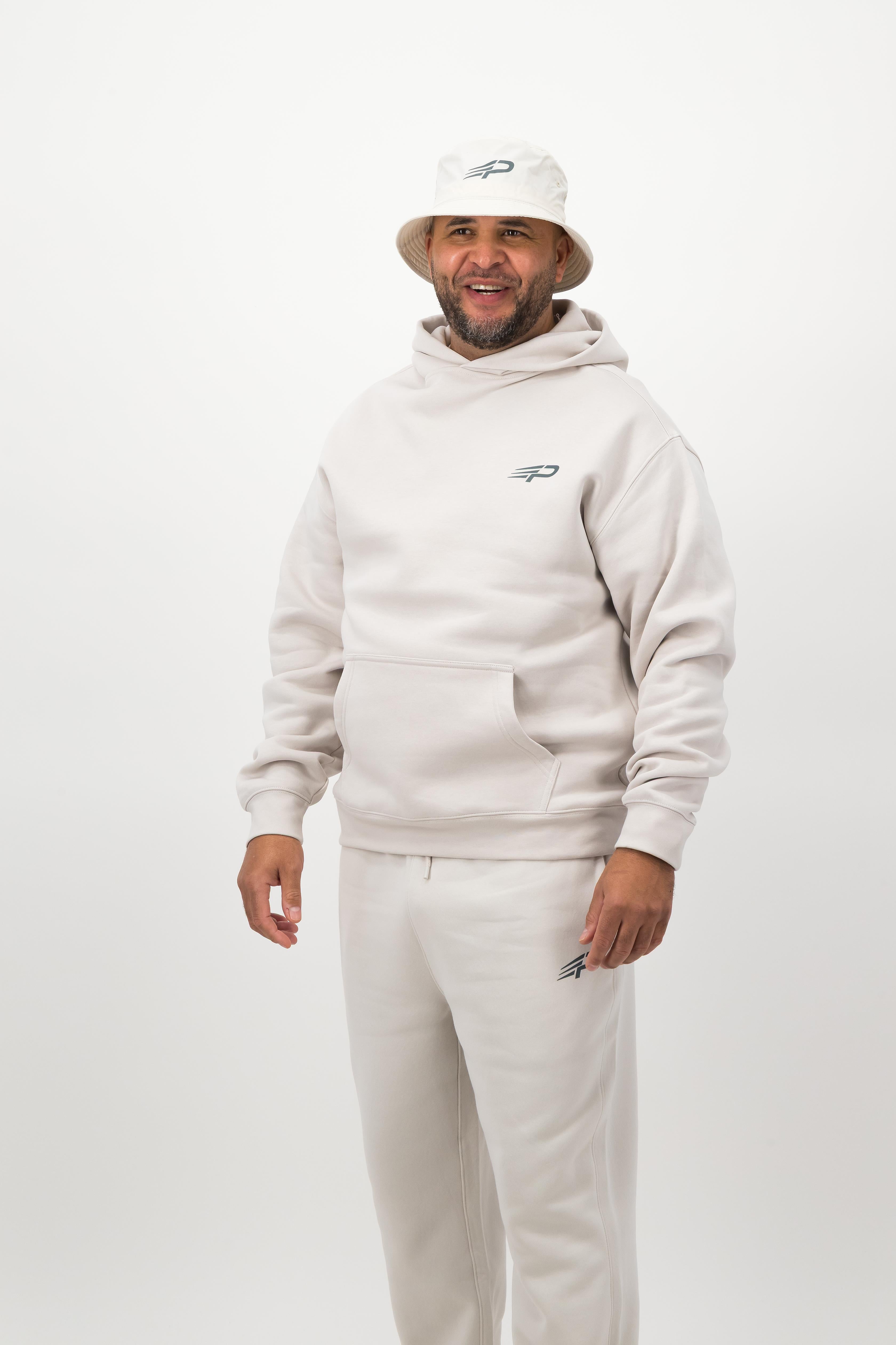 Person wearing a light hoodie, sweatpants and a bucket hat posing against a white background