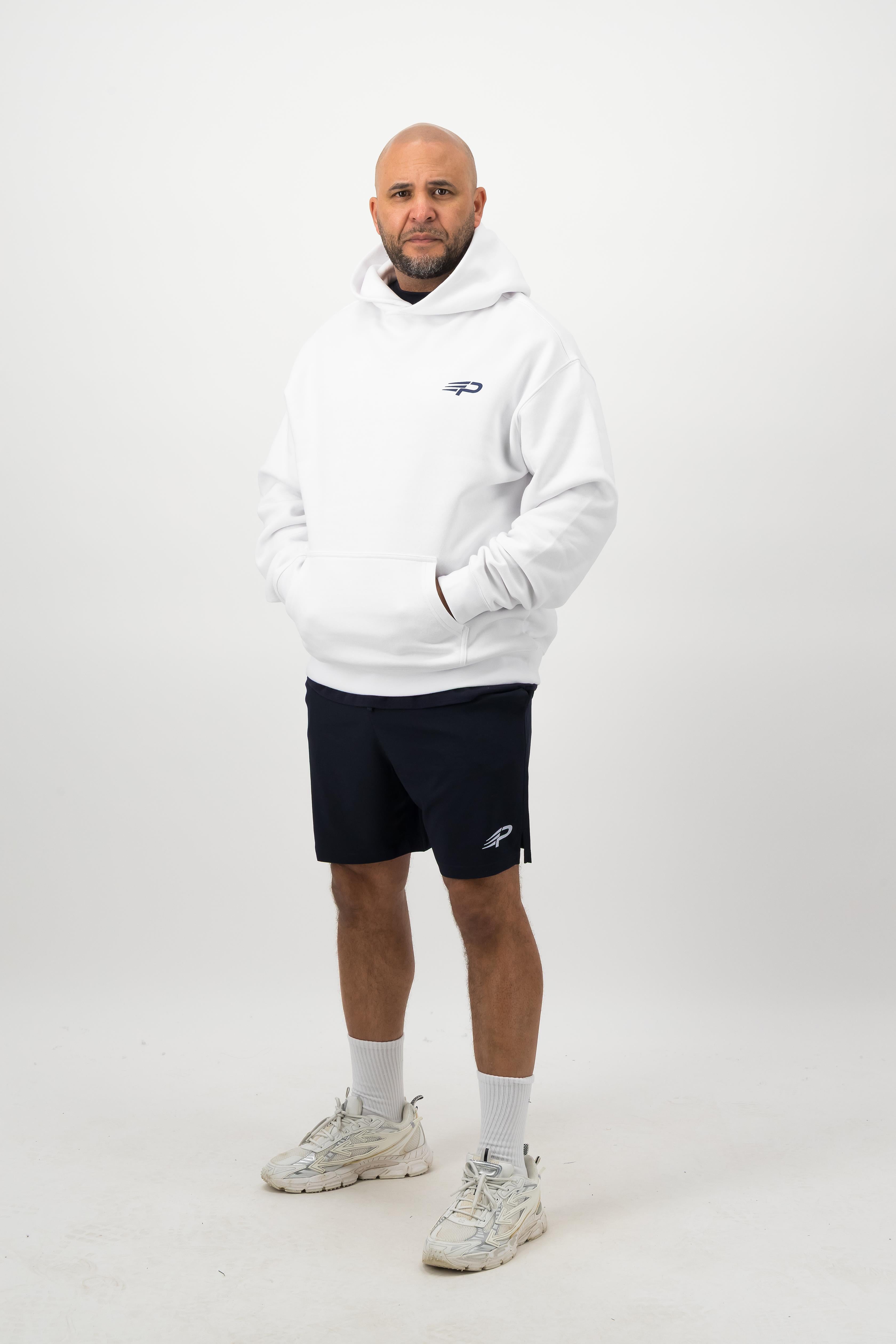 Person wearing a Concept Padel white rebound hoodie standing facing forward, styled with black shorts and trainers against a white background