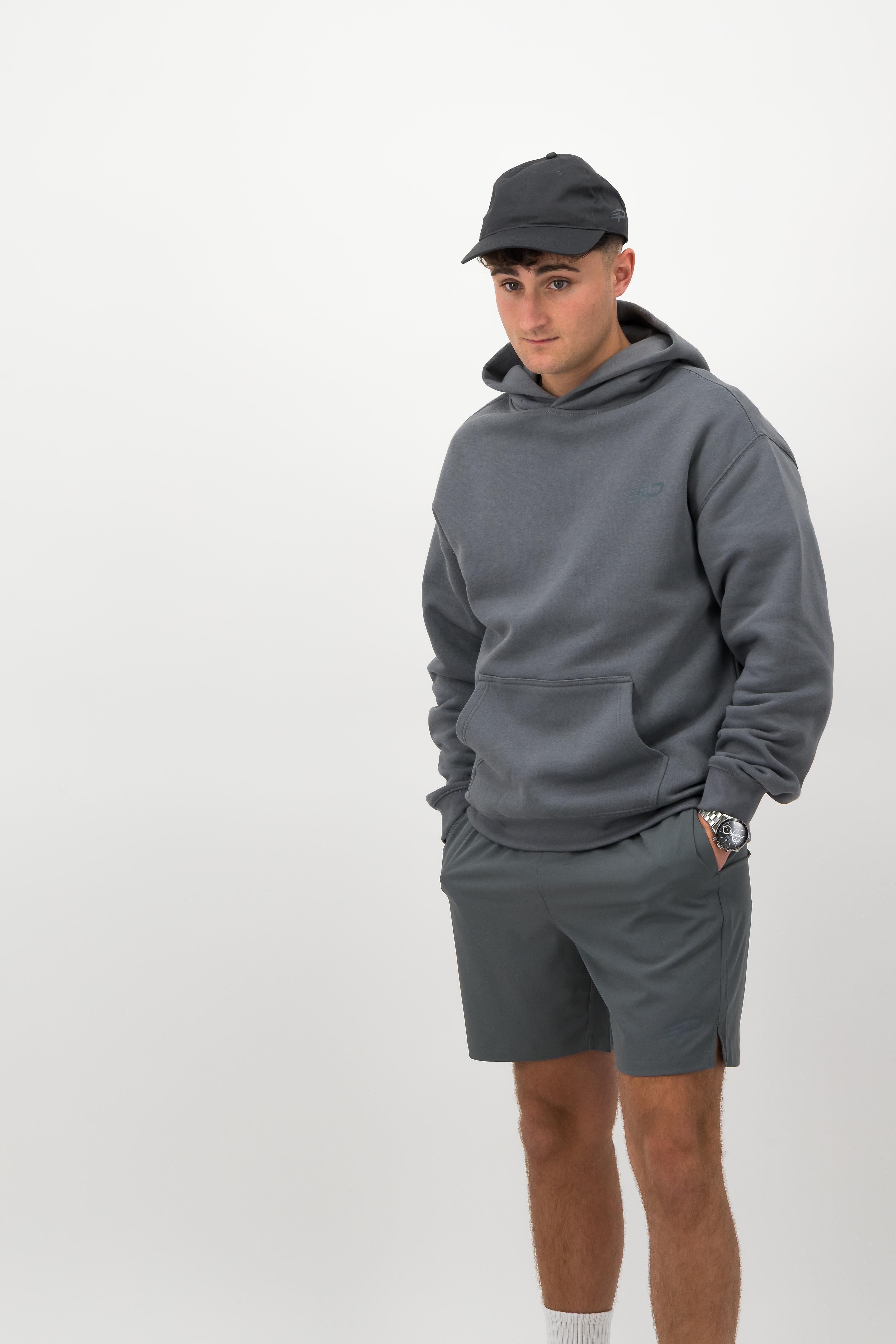 Man wearing coal Concept Padel cap with dark sweatshirt and shorts