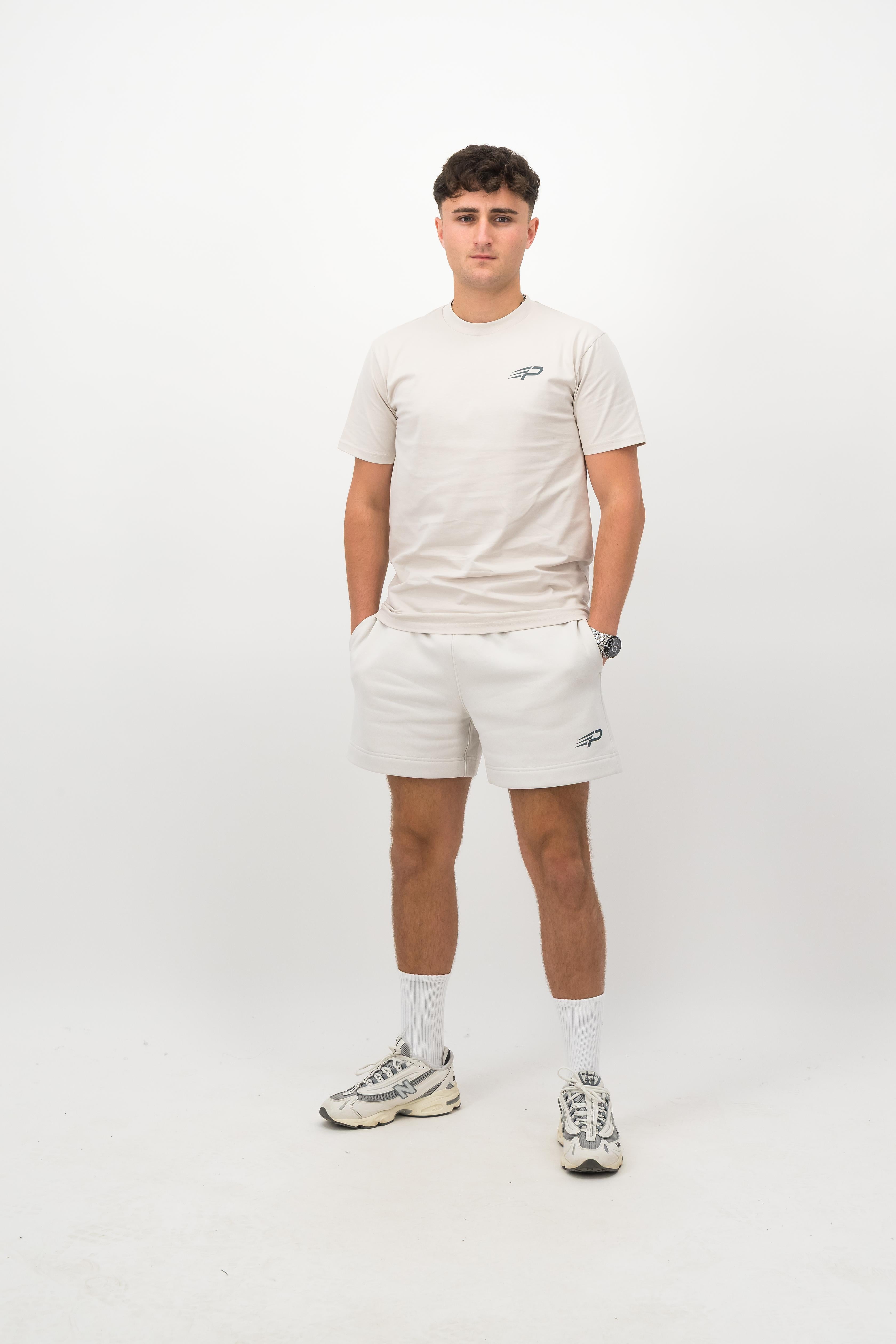 Person wearing a Concept Padel bone rebound tee standing facing forward, styled with white shorts and trainers against a white background