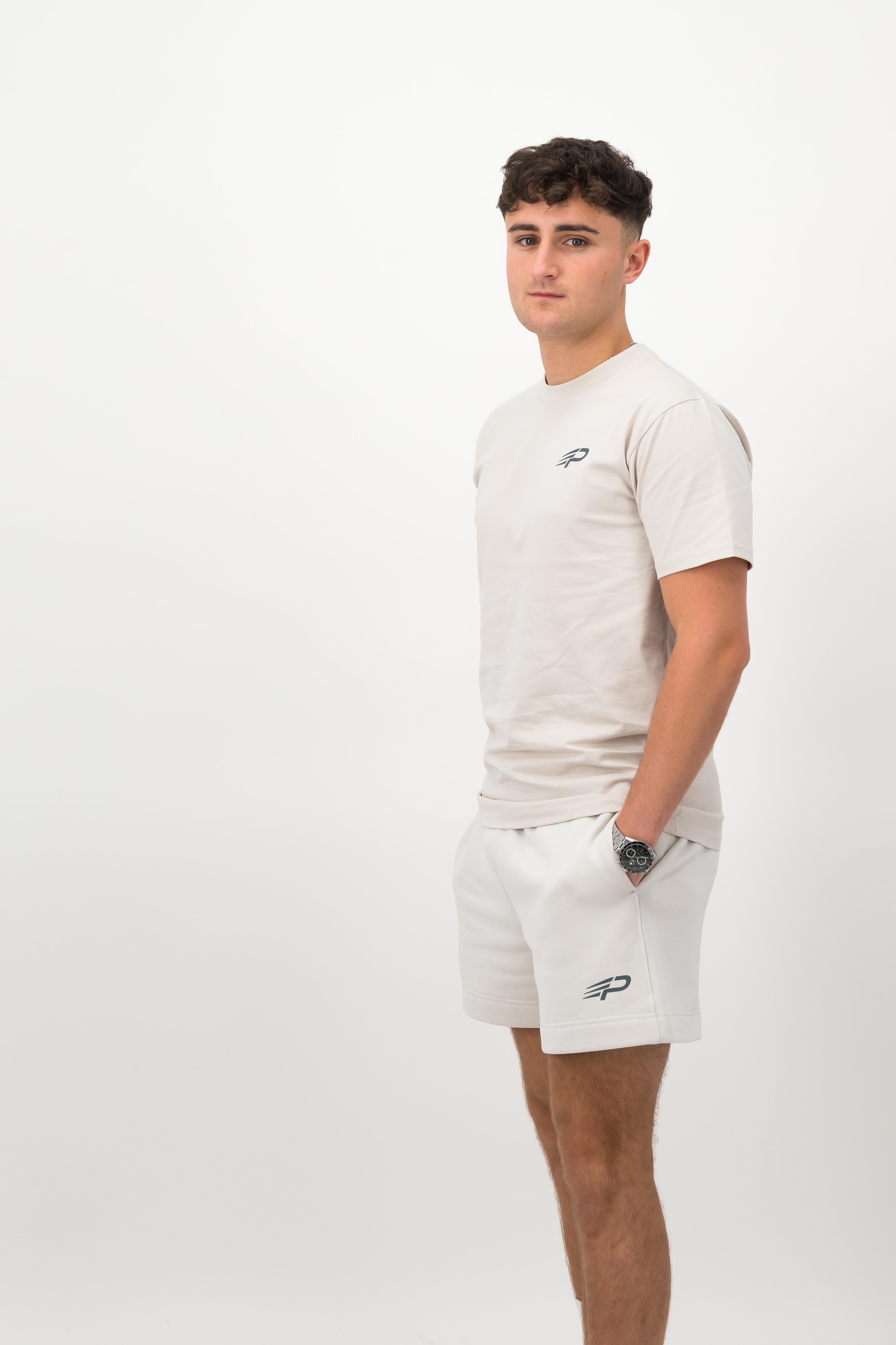 Person wearing a Concept Padel bone rebound tee standing side on, paired with white shorts and trainers against a white background