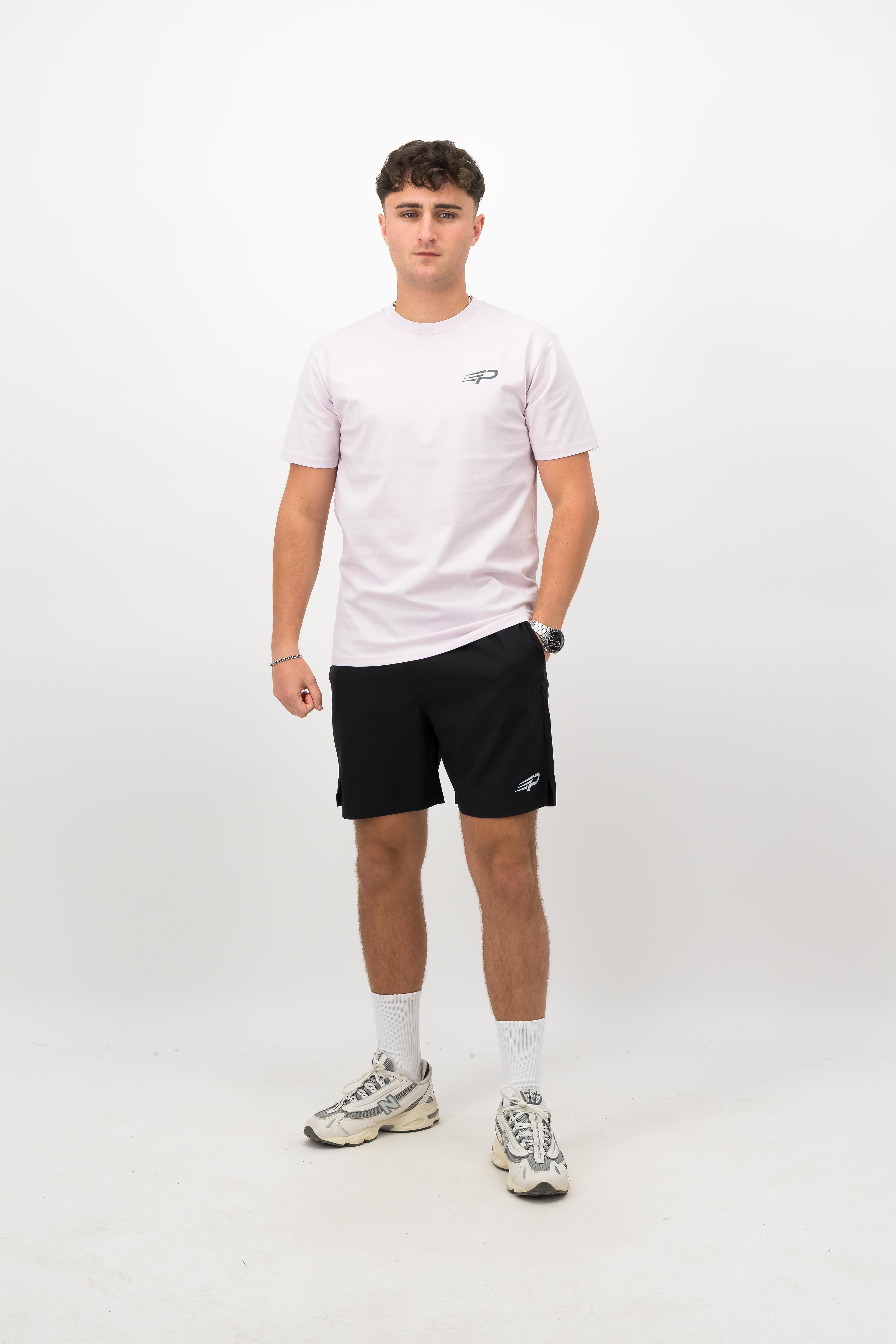 Person wearing a Concept Padel orchid rebound tee standing facing forward, styled with black shorts and trainers against a white background