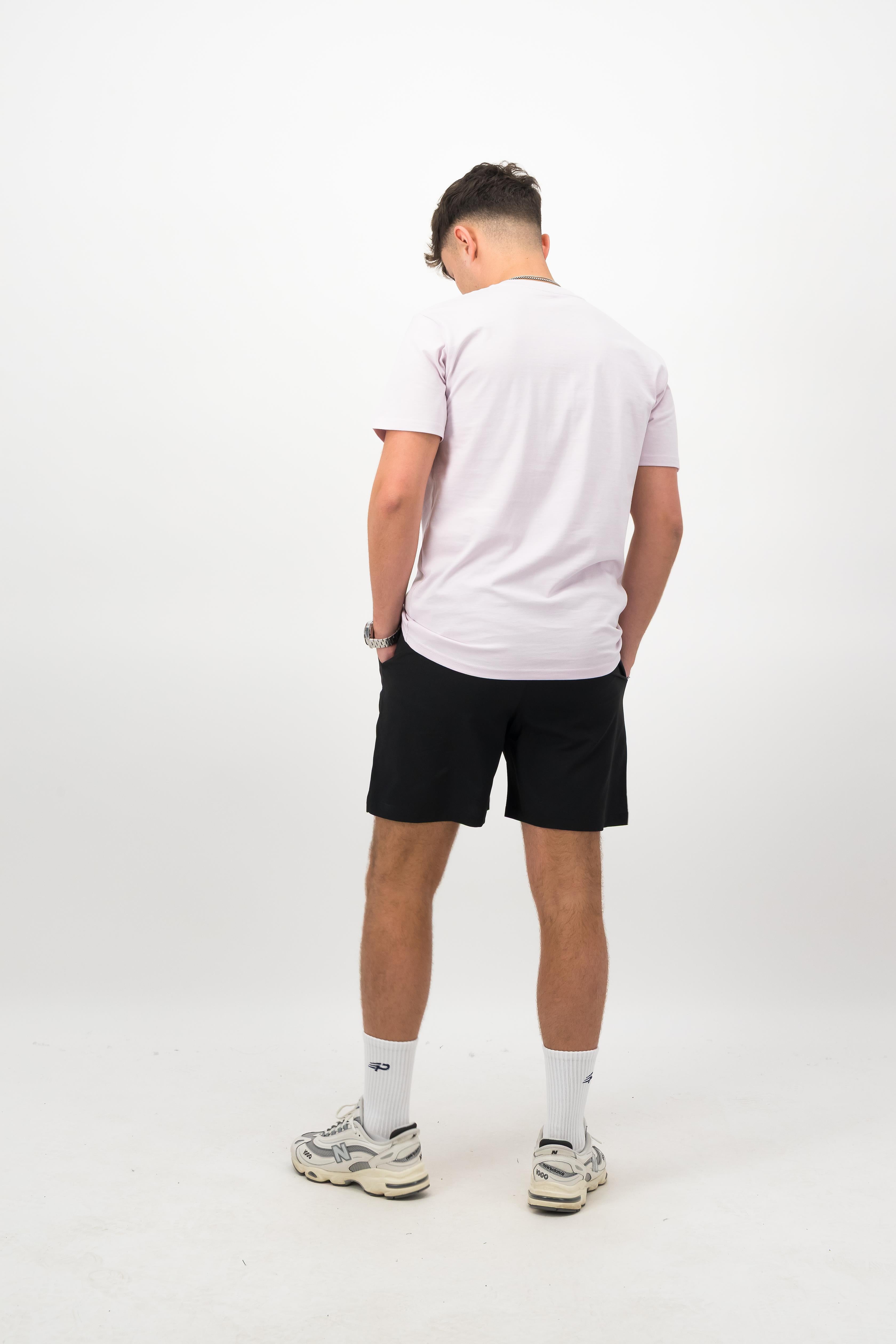 Person wearing a Concept Padel orchid rebound tee standing with back to camera showing the clean back silhouette, styled with black shorts and trainers against a white background