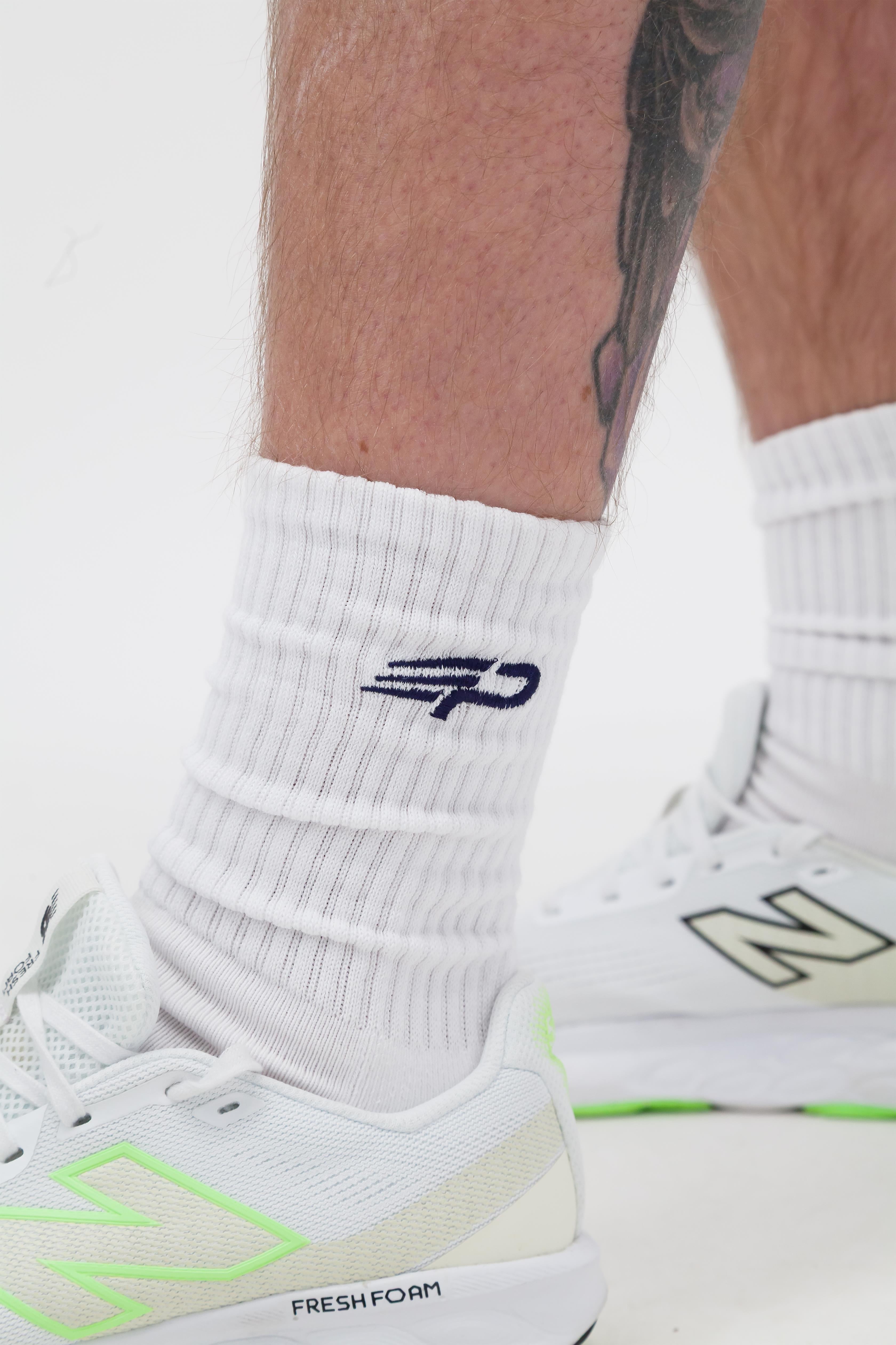 Side view of white Concept Padel everyday socks with blue logo and white trainers