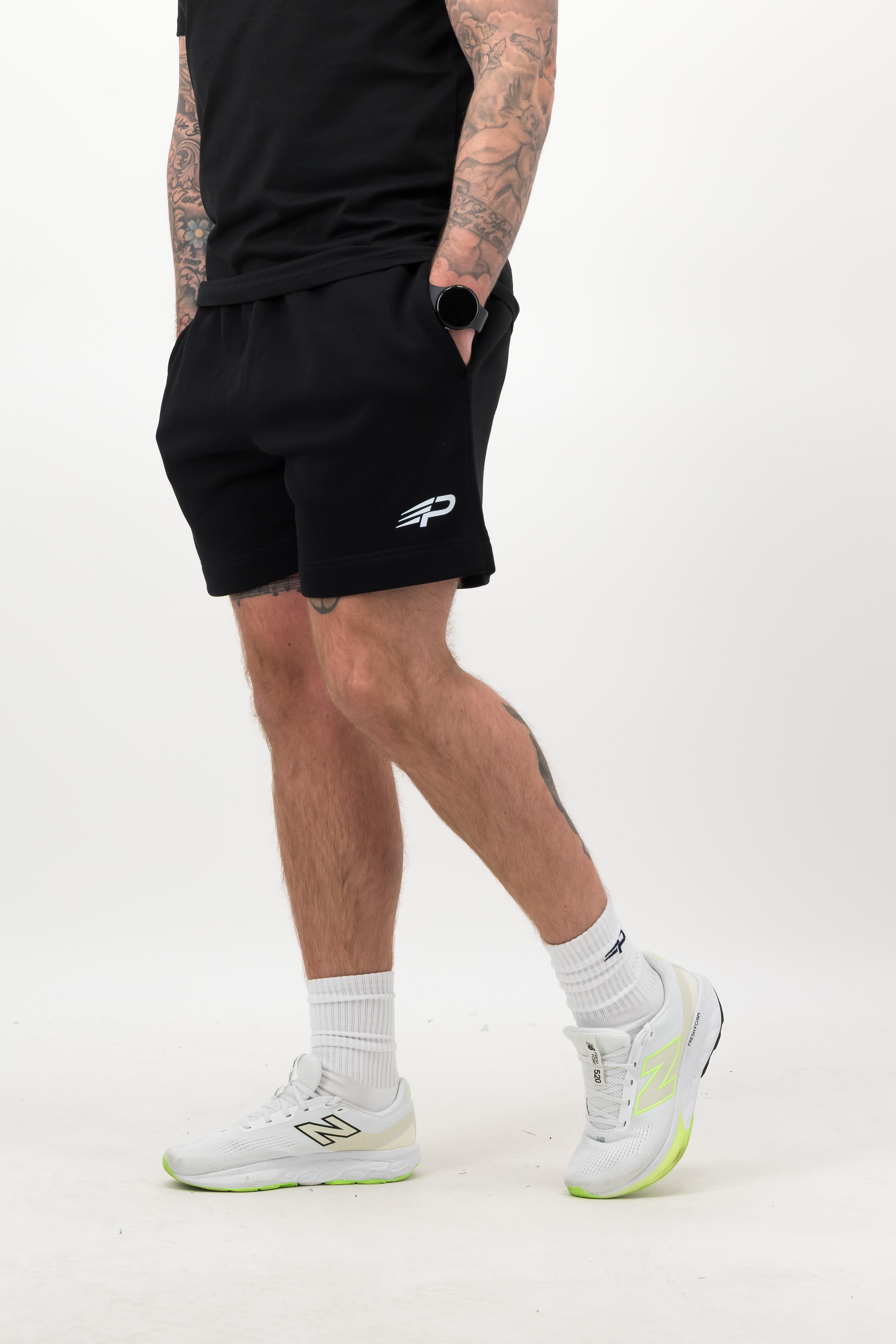 Lower‑leg view showing white Concept Padel everyday socks, black shorts and white trainers
