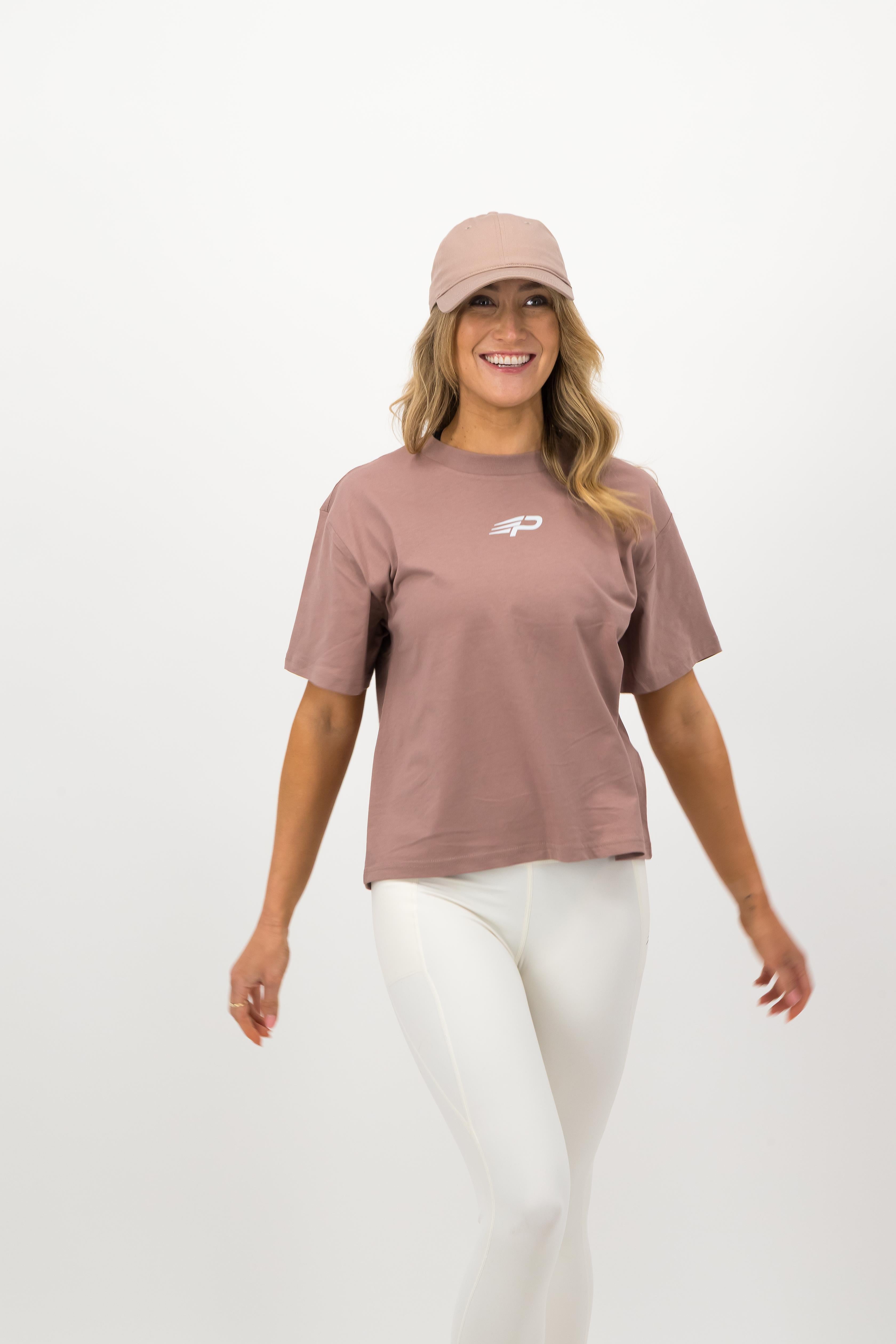 Back view of woman wearing hazy pink Concept Padel cap with white leggings