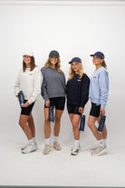 Group of women in athletic wear holding navy Concept Padel water bottles against a white background