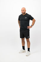 Person wearing Concept Padel black performance shorts standing side on, paired with black tee and trainers against a white background