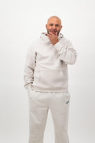 Man wearing Concept Padel bone sweatpants standing facing forward, styled with a matching sweatshirt and trainers against a white background