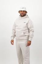 Person wearing a light hoodie, sweatpants and a bucket hat posing against a white background