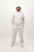 Man wearing Concept Padel bone sweatpants standing in a relaxed pose with arms by his sides, paired with a matching sweatshirt, bucket hat and trainers against a white background