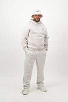 Person wearing a light hoodie, sweatpants and a bucket hat posing against a white background