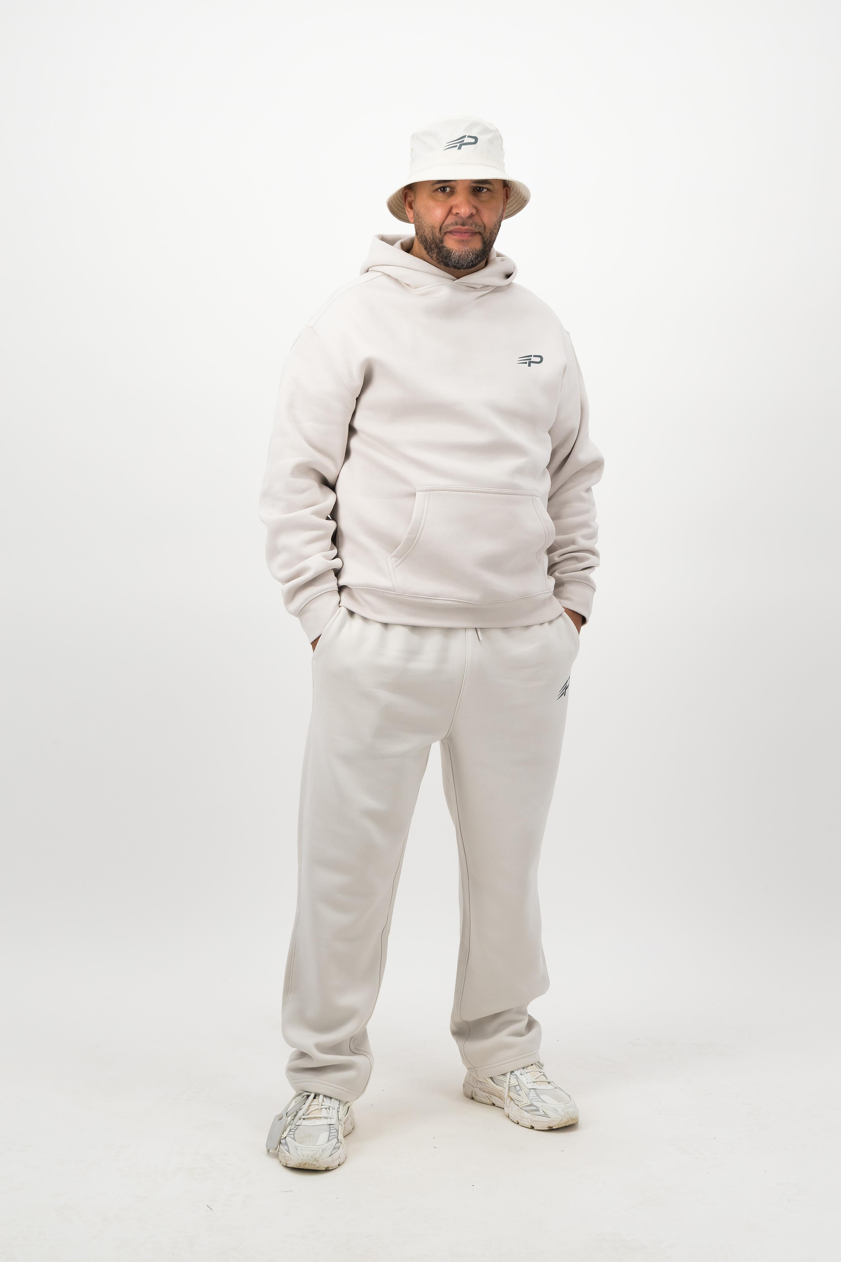 Person wearing a light hoodie, sweatpants and a bucket hat posing against a white background
