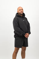 Person wearing a Concept Padel black faded hoodie standing side on, paired with black shorts and trainers against a white background