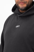 Close‑up of the Concept Padel logo on the black faded hoodie worn against a white background