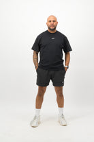 Person wearing a Concept Padel black faded tee standing facing forward, styled with black shorts and trainers against a white background