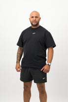 Person wearing a Concept Padel black faded tee standing facing forward, styled with black shorts and trainers against a white background