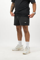 Person wearing Concept Padel black faded sweat shorts standing in a relaxed pose, paired with black tee and trainers against a white background