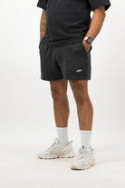 Person wearing Concept Padel black faded sweat shorts standing in a relaxed pose, paired with black tee and trainers against a white background