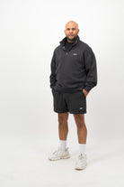 Person wearing Concept Padel black faded sweat shorts standing facing forward, styled with black tee and trainers against a white background
