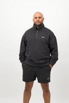 Person wearing Concept Padel black faded sweat shorts standing facing forward, styled with black zip up and trainers against a white background