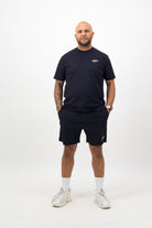 Person wearing a Concept Padel ink blue rebound tee standing facing forward, styled with matching shorts and trainers against a white background