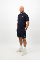 Person wearing a Concept Padel ink blue rebound tee standing side on, paired with matching shorts and trainers against a white background