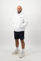 Person wearing a Concept Padel white rebound hoodie standing facing forward, styled with black shorts and trainers against a white background