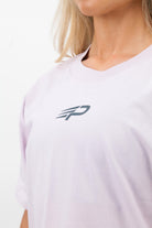 Close‑up of the Concept Padel logo on the orchid court tee worn by a woman against a white background