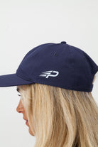 Person wearing a navy blue Concept Padel cap with a logo on a light background