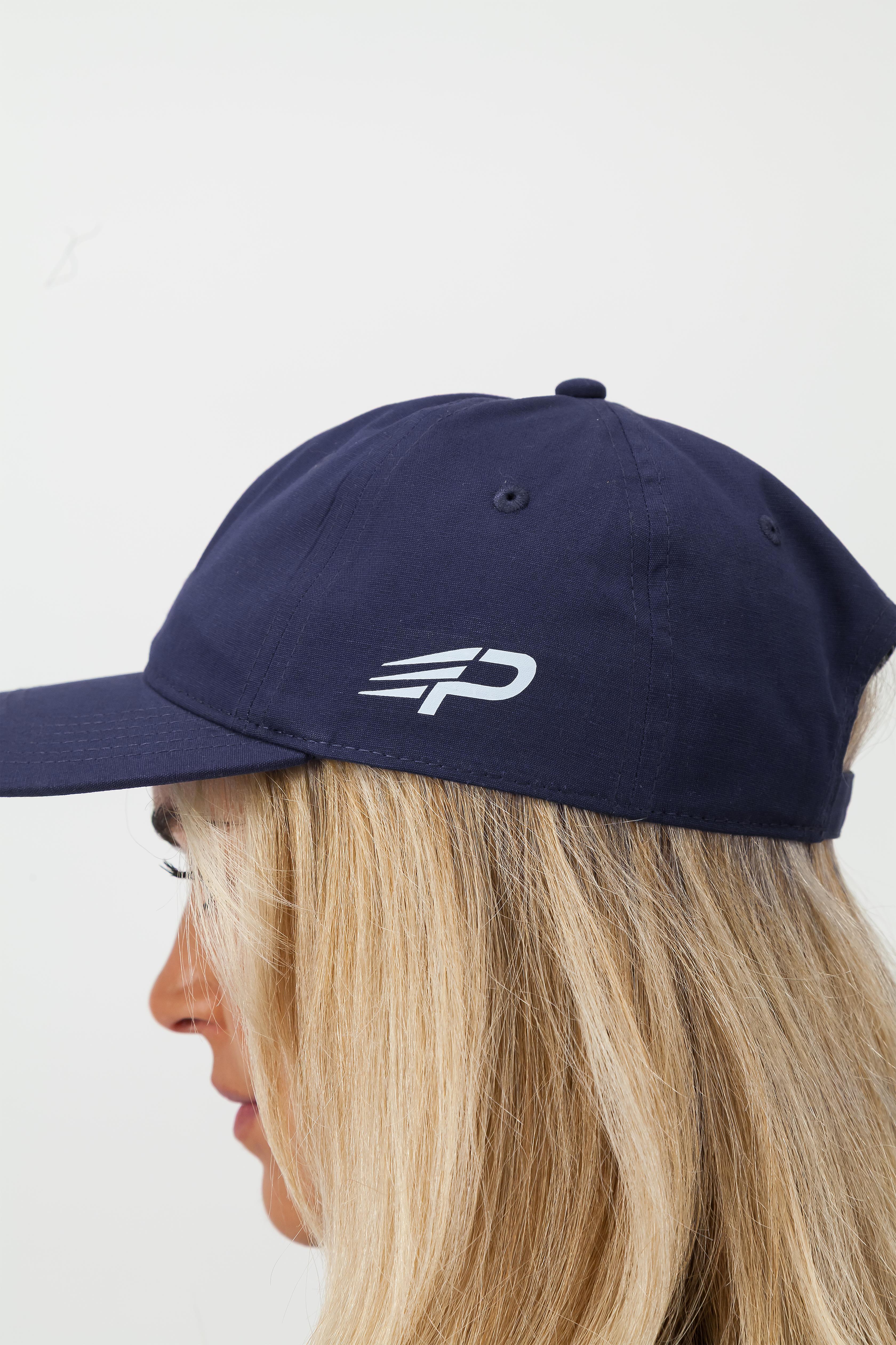 Person wearing a navy blue Concept Padel cap with a logo on a light background