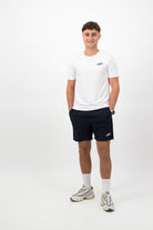 Person wearing a Concept Padel white performance tee standing facing forward, styled with dark shorts and trainers against a white background