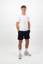 Person wearing a Concept Padel white performance tee standing facing forward, styled with dark shorts and trainers against a white background