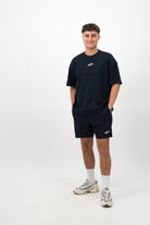 Person wearing Concept Padel ink blue performance shorts standing facing forward, styled with ink blue tee and trainers against a white background