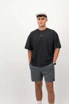 Man wearing ecru Concept Padel performance cap with black oversized T‑shirt and grey shorts front view