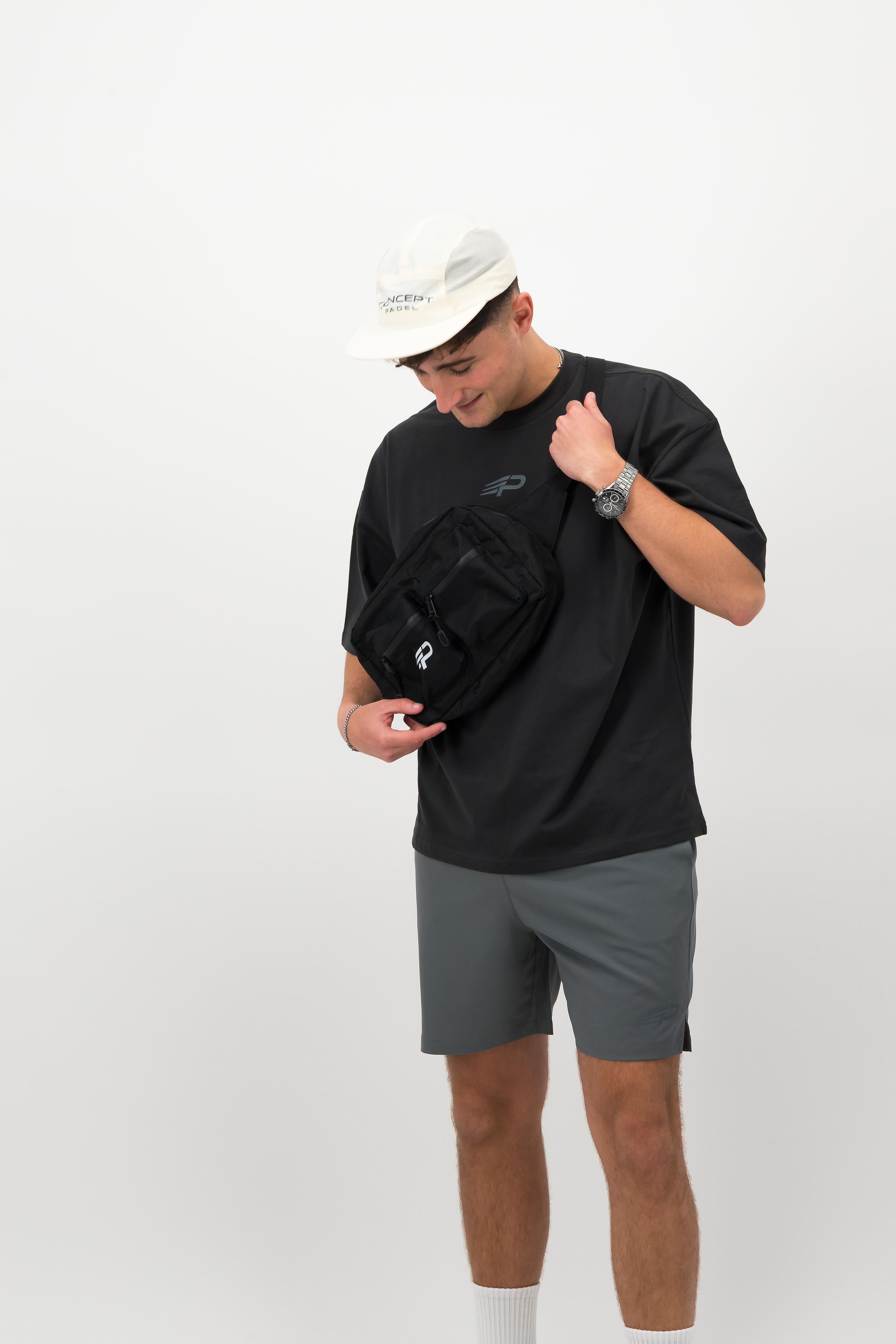 Side view of man wearing black Concept Padel body belt bag with casual athletic outfit