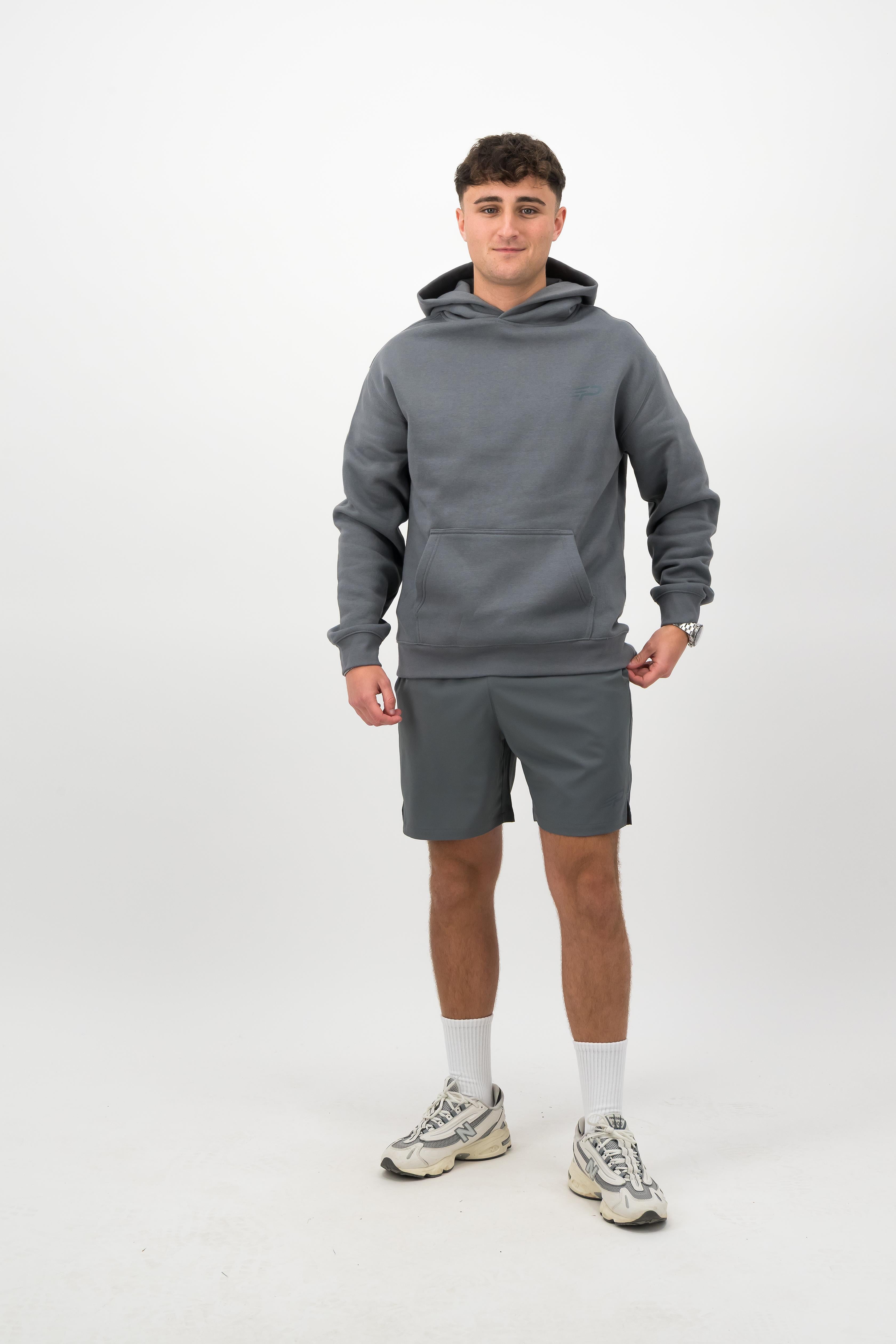 Person wearing a Concept Padel shadow rebound hoodie standing facing forward, styled with grey shorts and trainers against a white background