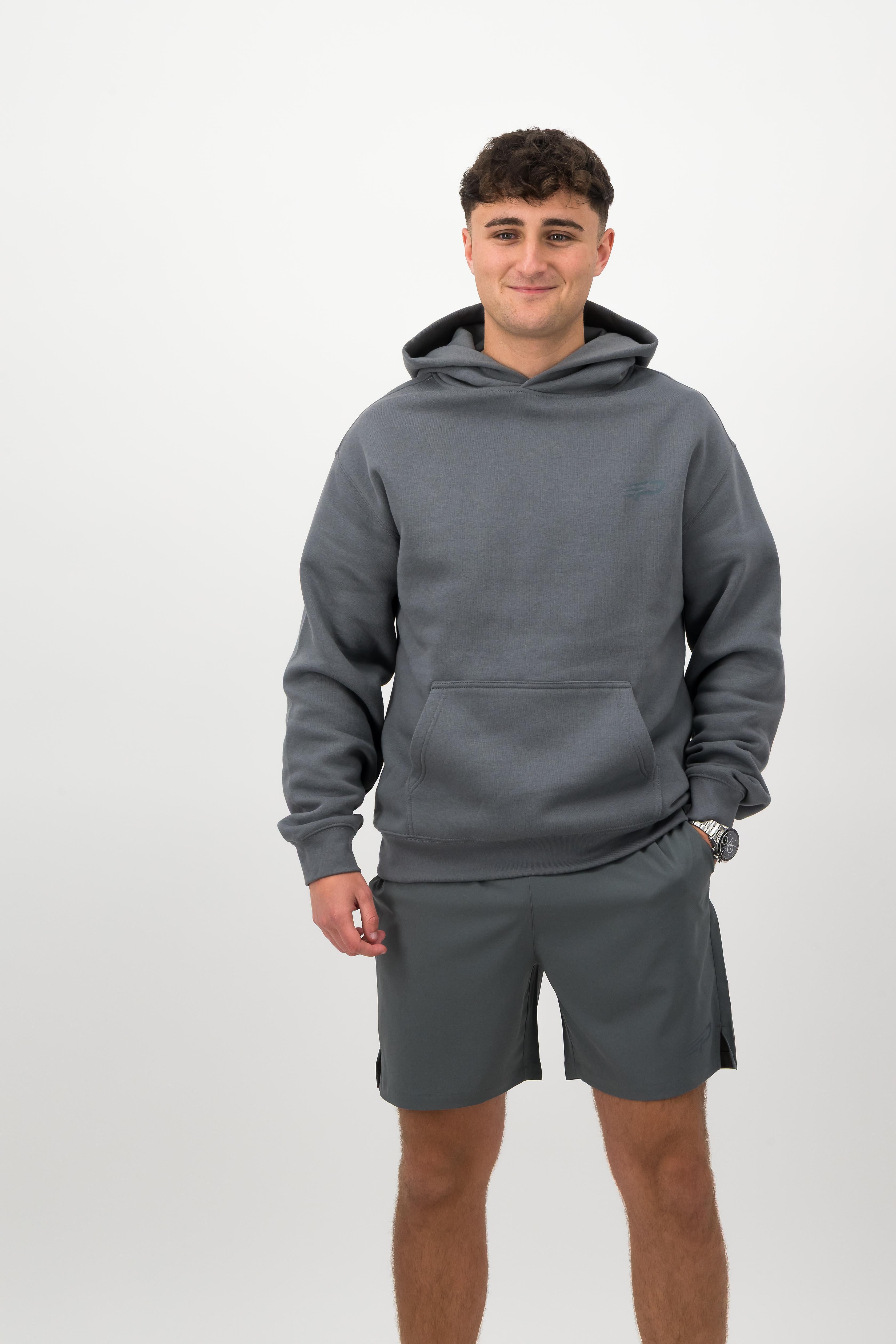 Person wearing a Concept Padel shadow rebound hoodie standing facing forward, styled with grey shorts and trainers against a white background