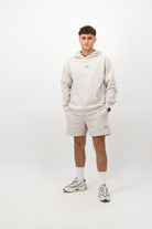 Person wearing a Concept Padel bone faded hoodie standing facing forward, styled with matching shorts and trainers against a white background