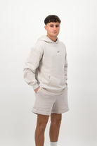 Person wearing a Concept Padel bone faded hoodie standing side on, paired with matching shorts and trainers against a white background
