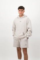 Person wearing a Concept Padel bone faded hoodie standing facing forward, styled with matching shorts and trainers against a white background