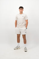 Person wearing a Concept Padel bone rebound tee standing facing forward, styled with white shorts and trainers against a white background