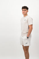 Person wearing a Concept Padel bone rebound tee standing side on, paired with white shorts and trainers against a white background