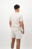 Person wearing a Concept Padel bone rebound tee standing with back to camera showing the clean back silhouette, styled with white shorts and trainers against a white background