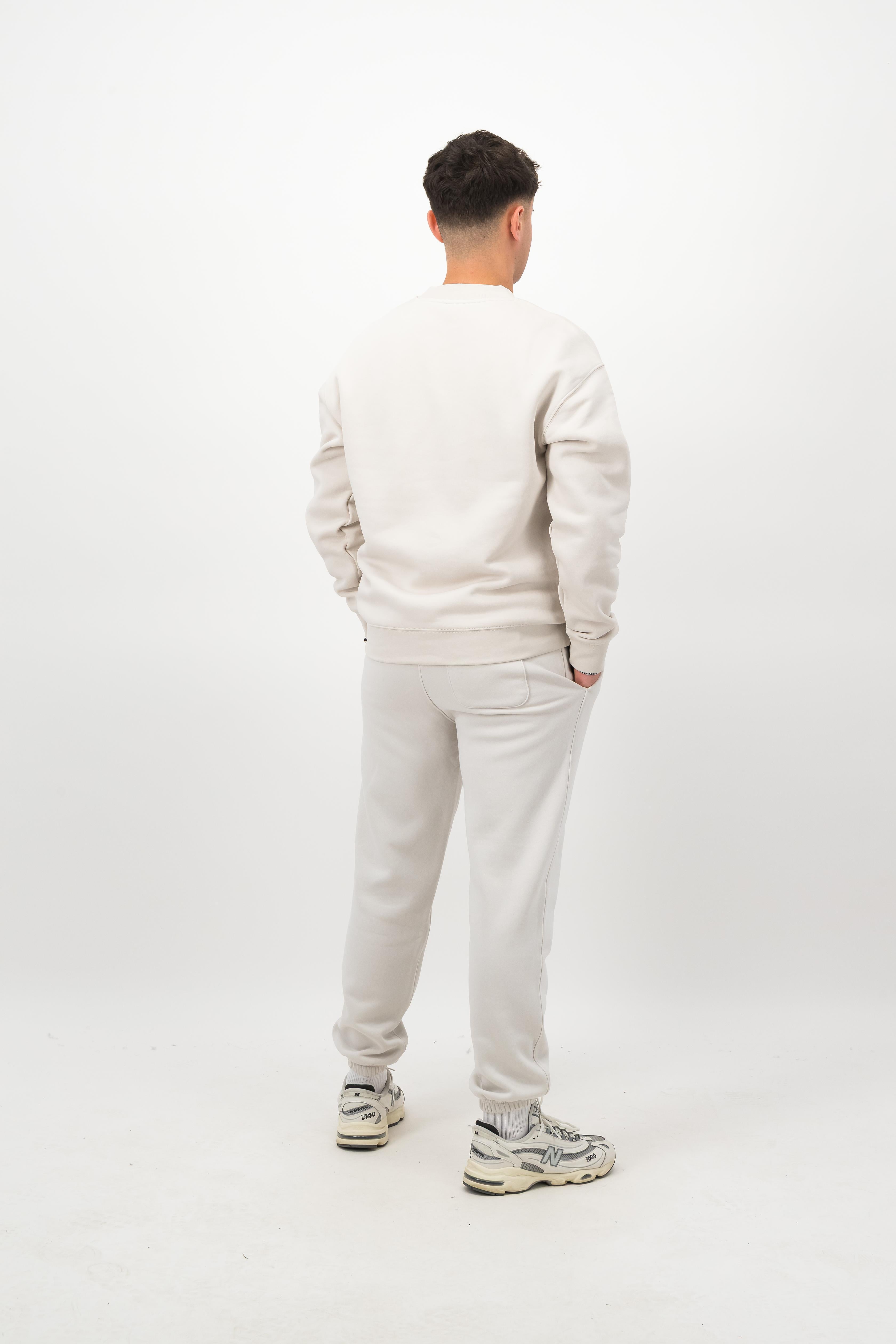 Person wearing Concept Padel bone rebound sweatpants standing with back to camera showing the clean back silhouette, styled with matching sweatshirt and trainers against a white background