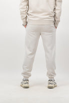Person wearing Concept Padel bone rebound sweatpants standing with back to camera showing the clean back silhouette, styled with matching sweatshirt and trainers against a white background
