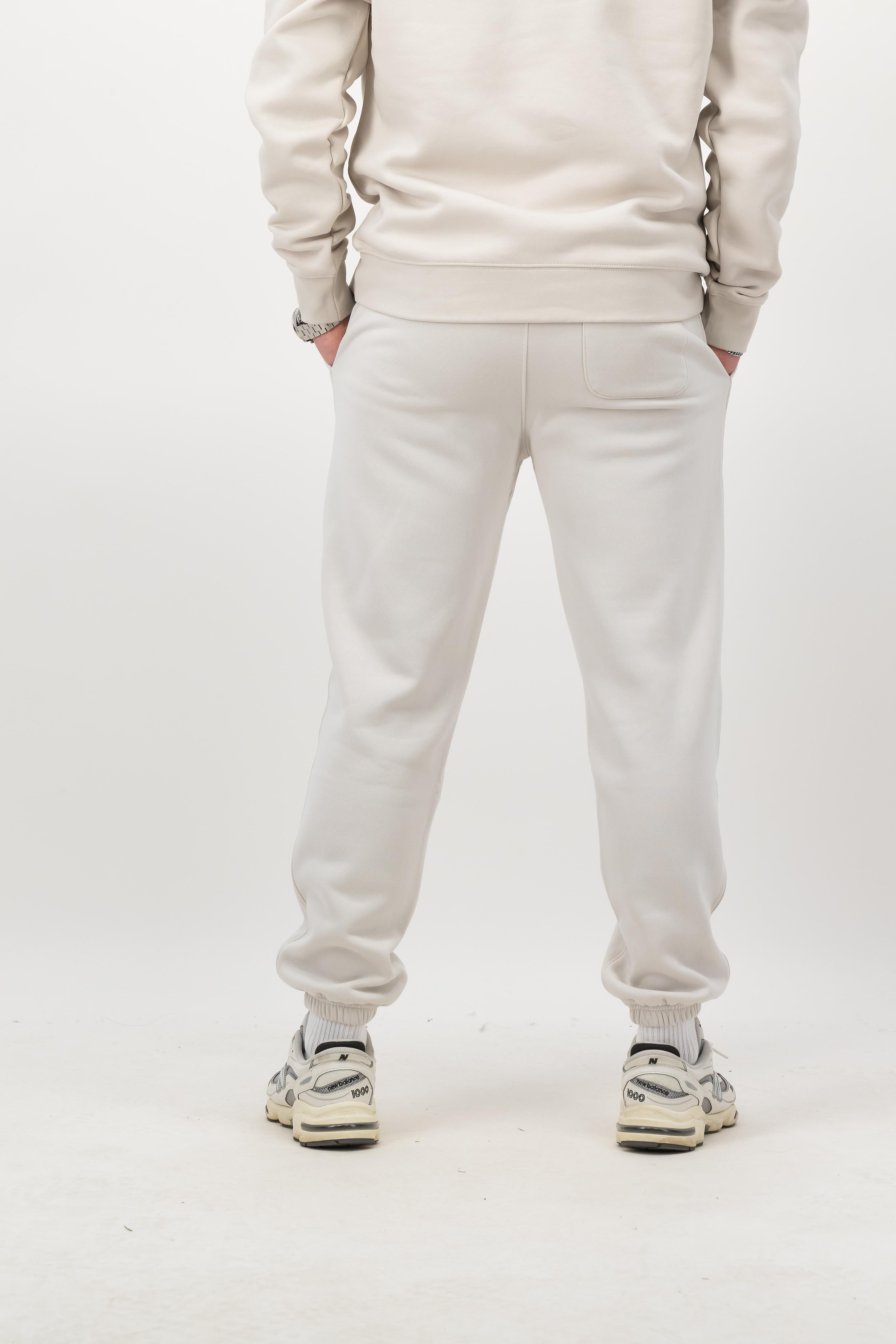 Person wearing Concept Padel bone rebound sweatpants standing with back to camera showing the clean back silhouette, styled with matching sweatshirt and trainers against a white background
