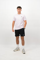 Person wearing a Concept Padel orchid rebound tee standing facing forward, styled with black shorts and trainers against a white background