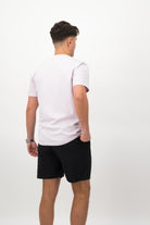 Person wearing a Concept Padel orchid rebound tee standing with back to camera showing the clean back silhouette, styled with black shorts and trainers against a white background