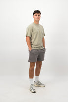 Person wearing a Concept Padel eucalyptus faded tee standing side on, paired with grey shorts and trainers against a white background